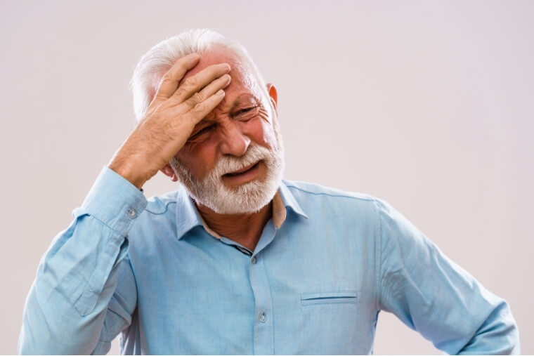 Older man experiencing headaches and ageing related pain.