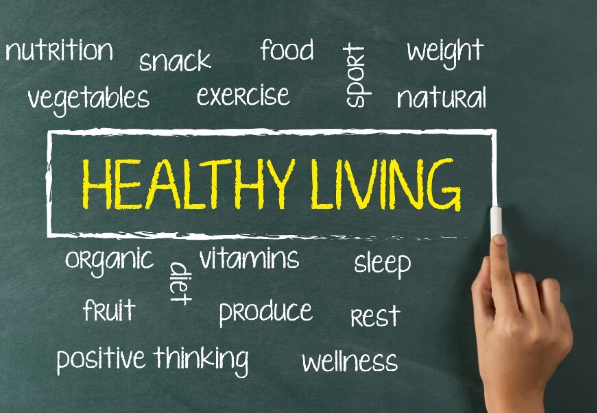 Chalkboard reading “Healthy Living” surrounded by words linked to common migraine triggers, including sleep, exercise, diet, nutrition and wellness.