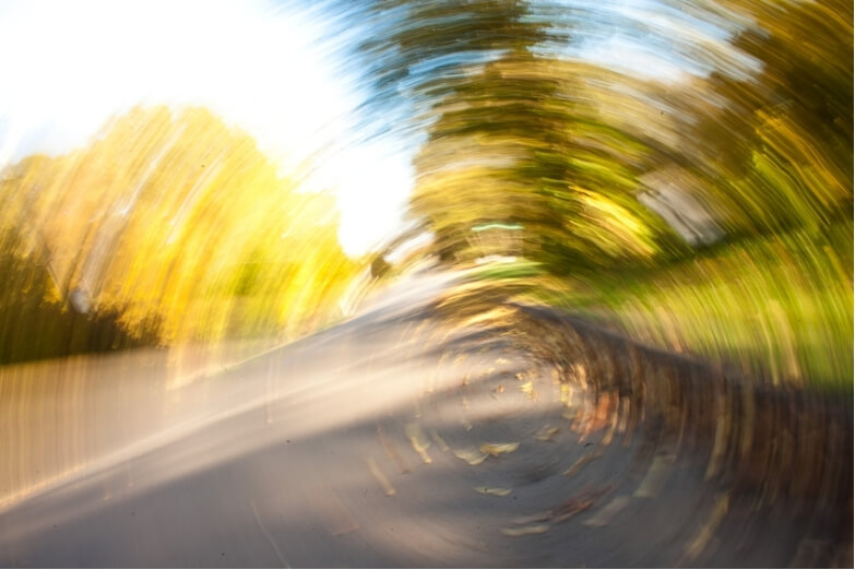 A swirling, blurred view of trees and road, illustrating the visual disorientation associated with cervicogenic dizziness.