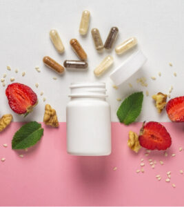 Flat lay of a white supplement bottle with assorted capsules, strawberries, walnuts, and sesame seeds—symbolising natural sources of electrolytes and nutritional support for headache prevention.