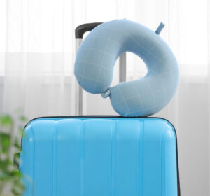 Neck pillow on suitcase, essential for preventing a flight headache during travel