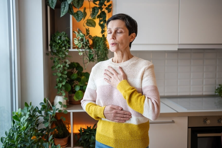 Woman practising calm diaphragmatic breathing at home to reduce breathing and headaches symptoms
