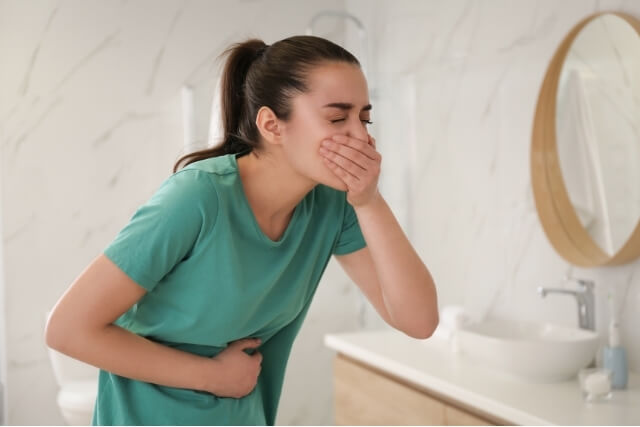 Woman experiencing stomach discomfort and nausea during a migraine attack
